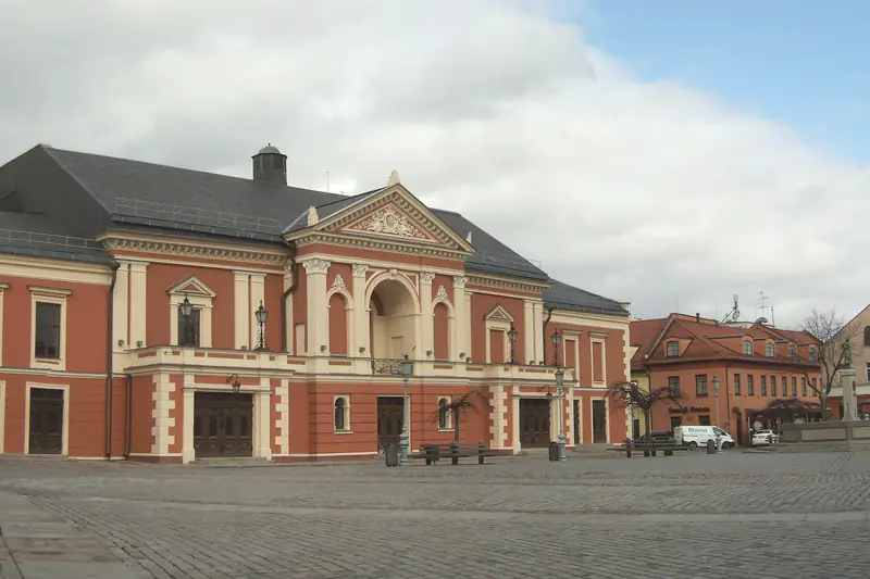 Raudonų plytų ir šviesaus tinko Klaipėdos dramos teatro pastatas su portiku; priešais – grįsta Teatro aikštė, dešiniau – senamiesčio namai.