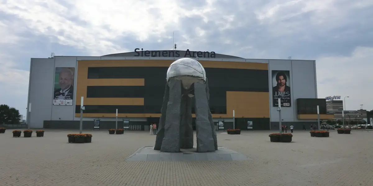 Arenos pastatas Ozo gatvėje Vilniuje: ant fasado – pavadinimas „Siemens Arena“ ir dvi didelės koncertų afišos, priešais – grįsta aikštė su skulptūra.